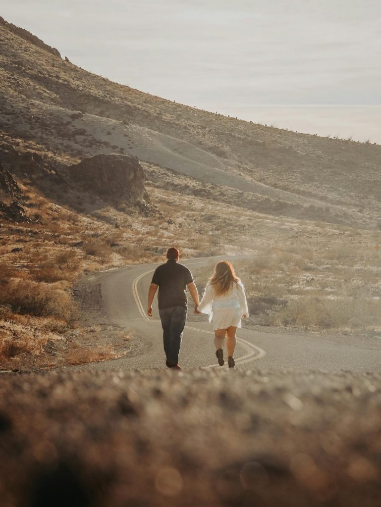 Two partners holding hands while walking down a sunlit path